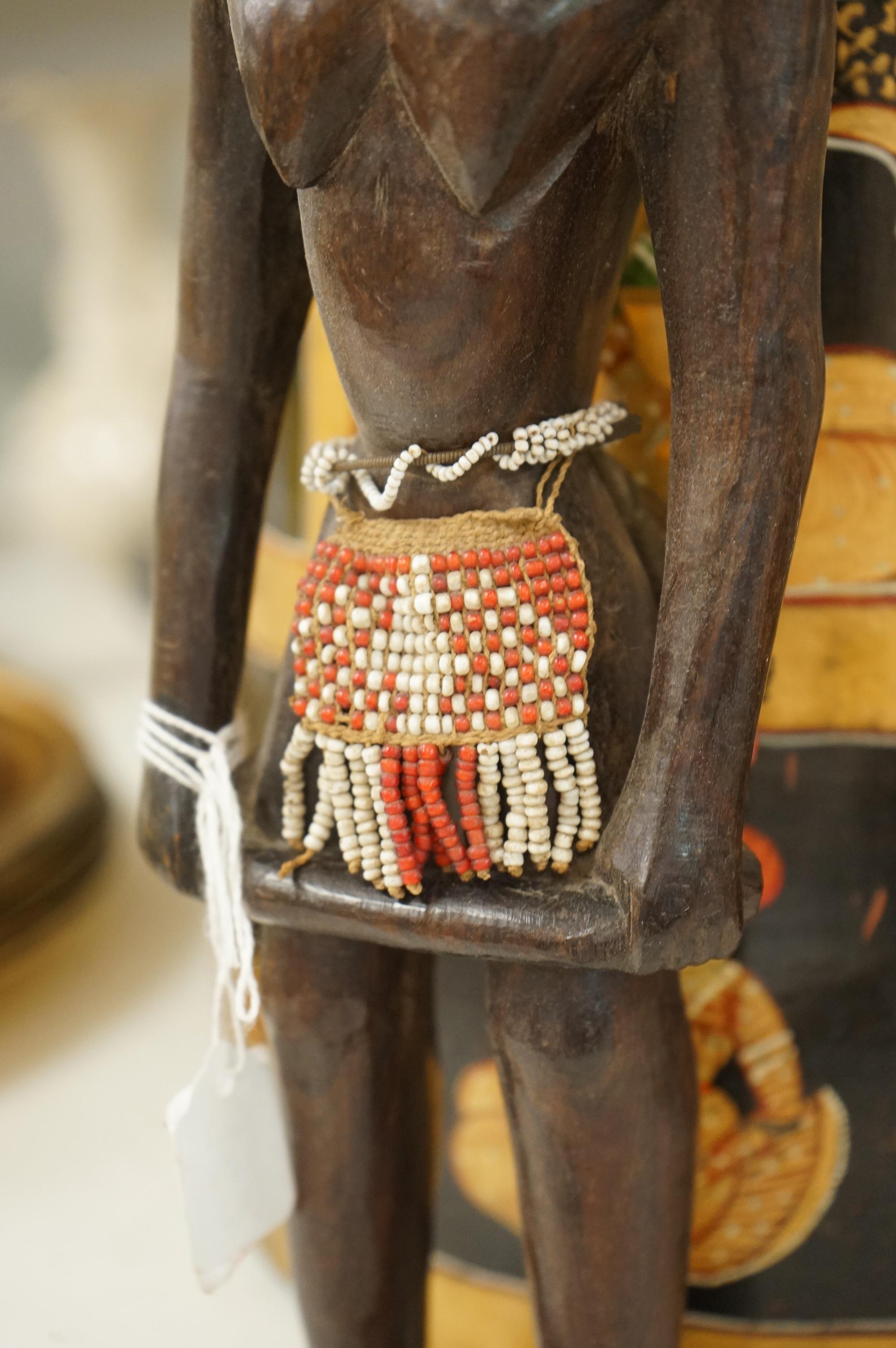 A collection of tribal and Asian collectables including a Tibetan prayer wheel, carvings, etc.